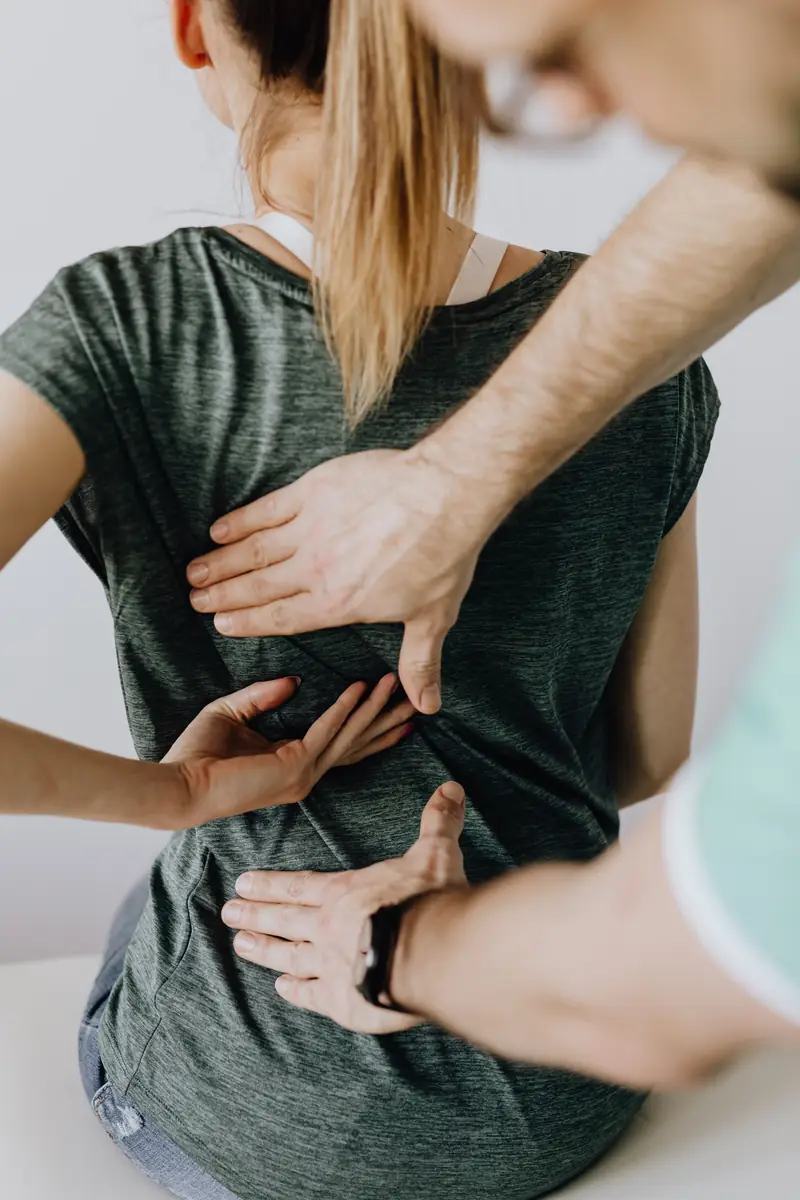 Profissional realizando atendimento manual de quiropraxia nas costas de uma pessoa